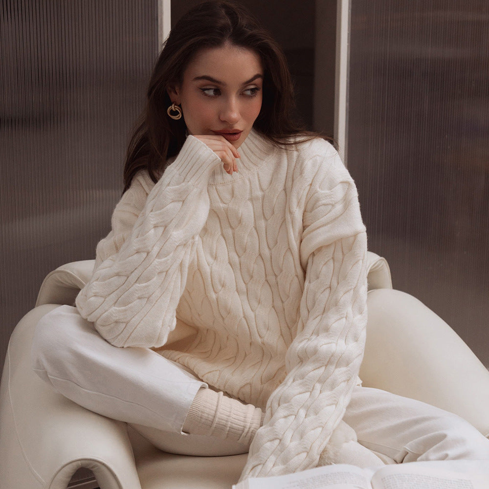 Woman wearing a white cable knit sweater sitting on a chair.